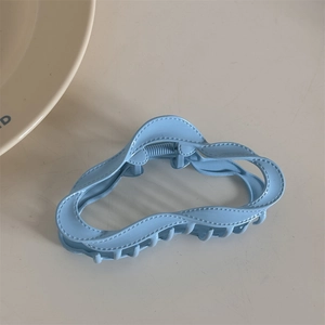 Detail of light blue alloy hair claw clip featuring wavy edge and stitching texture