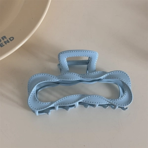Detailed view of a matte light blue alloy hair claw with stylish stitched texture