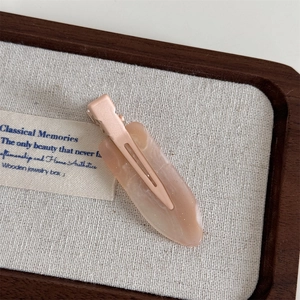 Macro shot of cream pink resin hair clip with marble texture in a wooden jewelry box