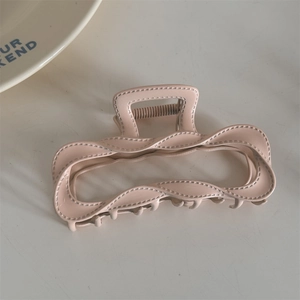 Close-up of matte nude pink hair claw clip with twisted wave edge and stitching details