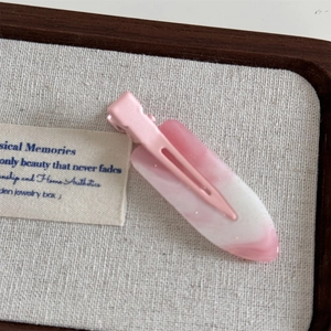 Macro detail of sweet pink marble resin hair clip with glitter on a wooden tray