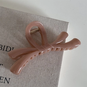 Gros plan d'une pince à cheveux rose en forme de nœud sur un tissu en lin