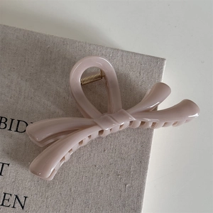 Vue détaillée de la pince à cheveux rose en forme de nœud avec son ressort en métal doré
