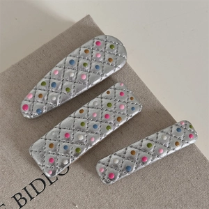 Set de trois barrettes en cuir argenté matelassé avec pois colorés sur tissu beige