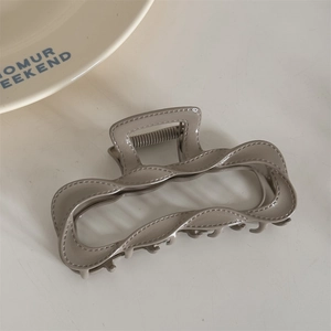 Detailed view of mocha grey alloy hair claw clip with stitch-textured wavy edges