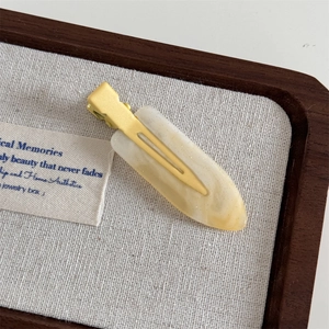Detail of cream marble resin hair clip on a textured linen display tray