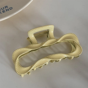 Top view of a cream yellow large twist hair claw clip on a clean white background