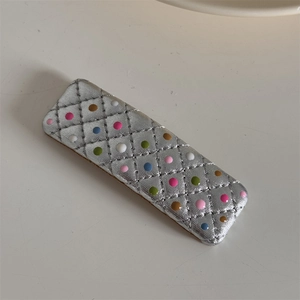 Détail d'une pince BB argentée à carreaux avec pois colorés sur fond blanc neutre