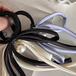 Detail of elegant satin bow hair ties with pearl pendants in black, beige and lavender