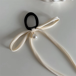 Close-up of silky cream satin bow scrunchie with a delicate white pearl pendant detail