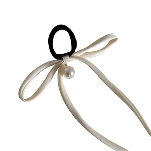 Elegant cream silk bow hair tie with large white pearl pendant on minimalist white background