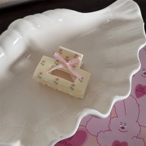Détails de motifs floraux et nœud en ruban rose sur une pince à cheveux jaune crème