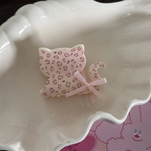 Détail de la pince à cheveux chat rose léopard avec un nœud en ruban dans un plateau coquillage