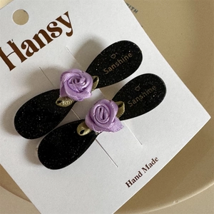 Dettaglio di fermagli per capelli con rose in seta viola su vassoio in ceramica beige