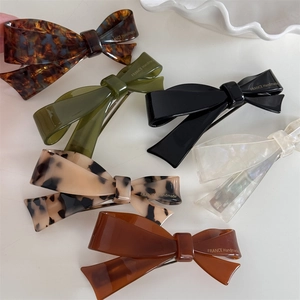 French style acetate bow hair clips in six elegant colors on a white decorative plate