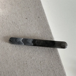 Macro detail of ink-wash marble pattern acetate hair clip on rustic fabric background