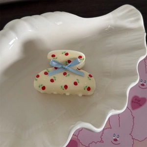 Détail d'une pince à cheveux crème à motif floral cerise avec un nœud en soie bleu clair