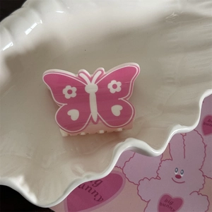 Détail de la pince à cheveux papillon rose avec motifs de fleurs et de cœurs