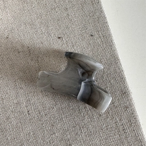 Detail shot of mini acetate hair claw clip with grey ink marble texture on linen fabric