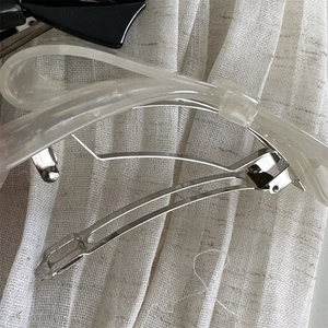 Macro detail of silver metal spring clip mechanism on acetic acid bow hair clip