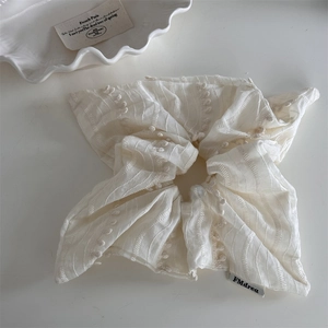 Detail of cream white pleated scrunchie with mini ball lace trim and striped texture