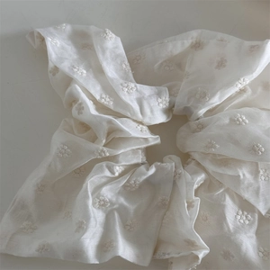 Detailed view of cream white floral embroidered scrunchie with elegant French style texture