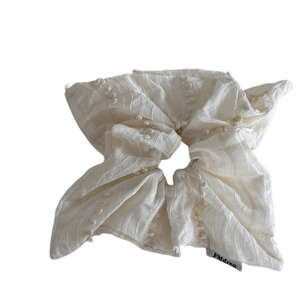 Creamy white textured scrunchie with 3D polka dots and minimalist fabric label for hair