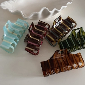 Macro detail of high-quality acetate hair claw clips with elegant stripes and marble textures