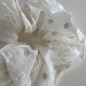 Detailed view of cream chiffon scrunchie featuring delicate floral embroidery and elegant pleats