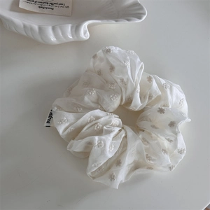 Detailed macro view of white organza scrunchie featuring elegant floral embroidery