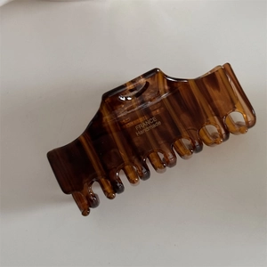 Close-up of brown acetate hair claw clip with gold France Handmade logo and sturdy teeth