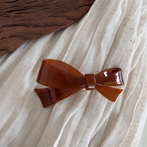 Detailed close-up of amber acetate bow hair clip with gold France Handmade lettering