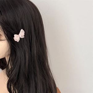 Dettaglio del fermaglio a farfalla rosa in acetato tra i capelli neri lunghi