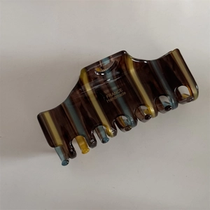 Detail of elegant striped acetate hair claw clip with golden France Handmade logo engraving