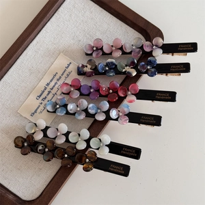 Six-piece set of acetate flower hair clips with sparkling rhinestones in a wooden tray