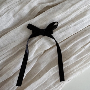 Vue détaillée du nœud en soie noire avec de longs rubans sur un tissu blanc