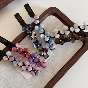 Detailed macro of acetate flower hair clips with rhinestones and handmade gold lettering