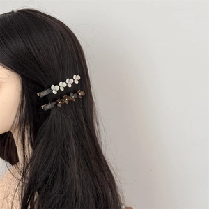 Elegant acetate flower hair clips in pearl white and tortoiseshell on black hair
