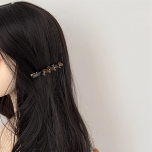 Detail view of acetate flower hair clip with France Handmade text and sparkling rhinestones