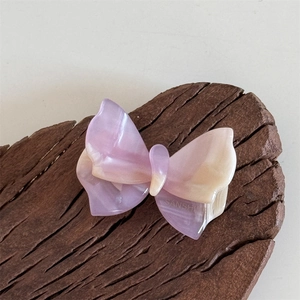 Dettaglio del fermaglio a farfalla in acetato con sfumatura perlata viola e gialla