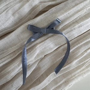Vue détaillée de la pince à cheveux nœud gris foncé avec texture tissu métallisé