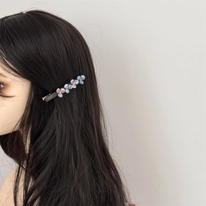 Detailed view of acetic acid flower hair clip on dark hair with handmade engraving