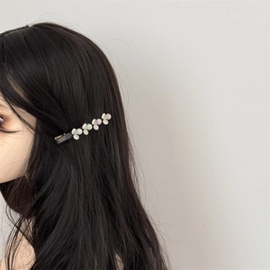 Detail view of acetate flower hair clip with gradient petals and gold lettering engraving