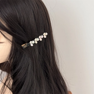 Detail view of acetate flower hair clip with golden France Handmade lettering on black base