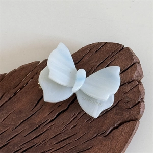 Dettaglio di un fermaglio per capelli a farfalla in acetato blu con logo SANSHINE