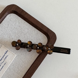 Detail of handmade acetate flower hair clip with amber texture and gold lettering