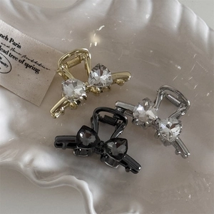 Detailed view of mini butterfly hair clips with heart crystals in gold, silver, and black