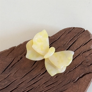 Vista macro di un fermaglio a farfalla in acetato marmorizzato giallo su legno