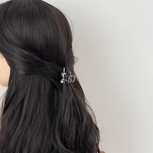 Elegant silver bow hair claw clip with rhinestones worn by a model in a half-up hairstyle