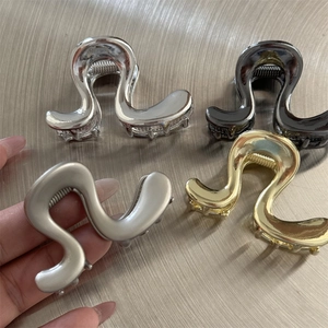 Détail de pinces à cheveux en métal ondulé en finitions argentée, dorée et noire